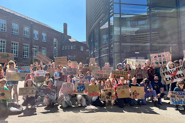 A group of around 30 student activists at Durham University protest outside the library holding colourful placards with Fossil Free Careers slogans