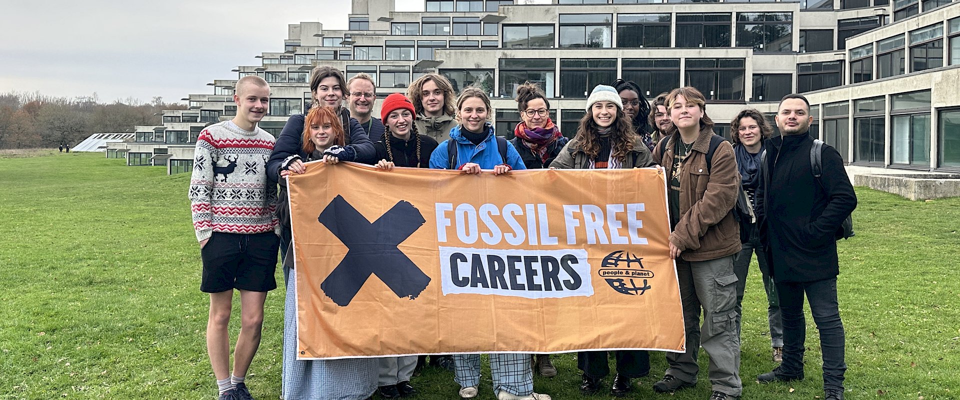 Image of students standing on steps outside of Swansea univeristy building and holding a Fossil Free Careers banner.