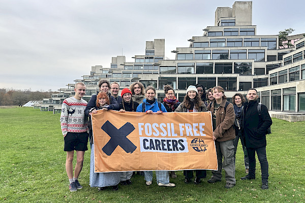 Image of students standing on steps outside of Swansea univeristy building and holding a Fossil Free Careers banner.