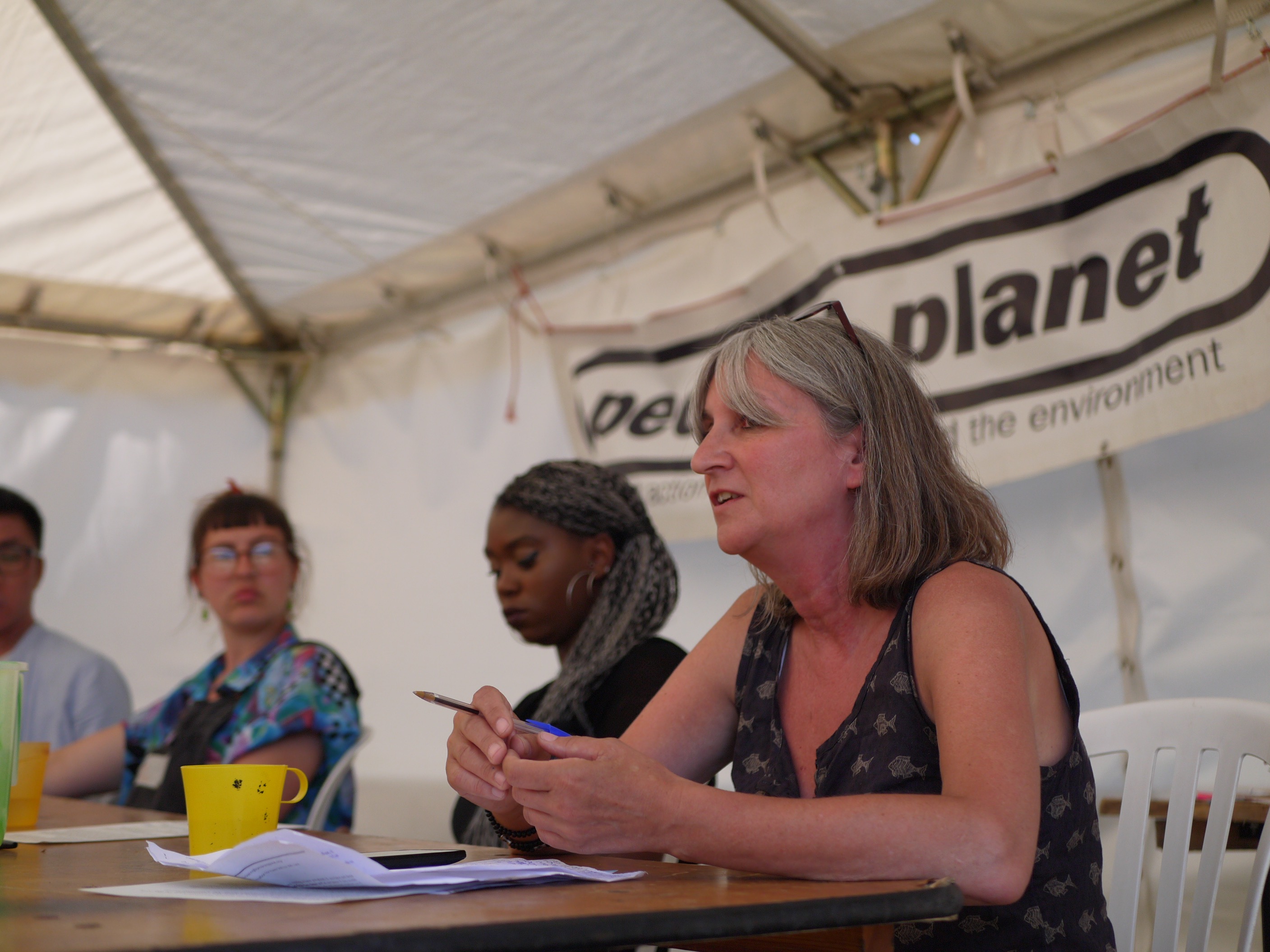A panel of speakers sits in front of a People & Planet banner.