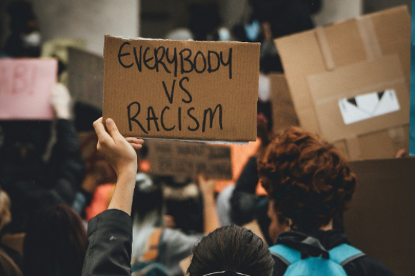 Crowds with person holding up sign that reads "Everybody vs racism"