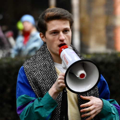 Image of Sam Gee holding megaphone speaking outdoors