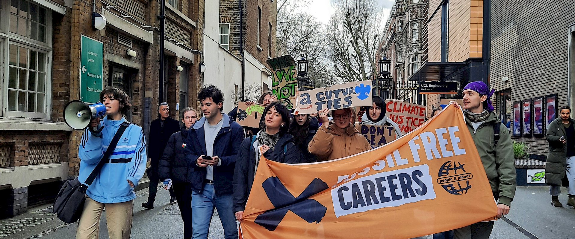 Students with fossil free careers banner and megaphone chanting through city streets