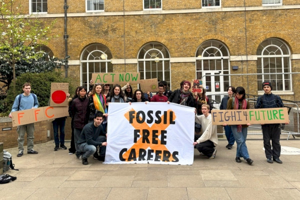 Crowd of students outside UCL building hold up handmade signs and giant banner reading Fossil Free Careers