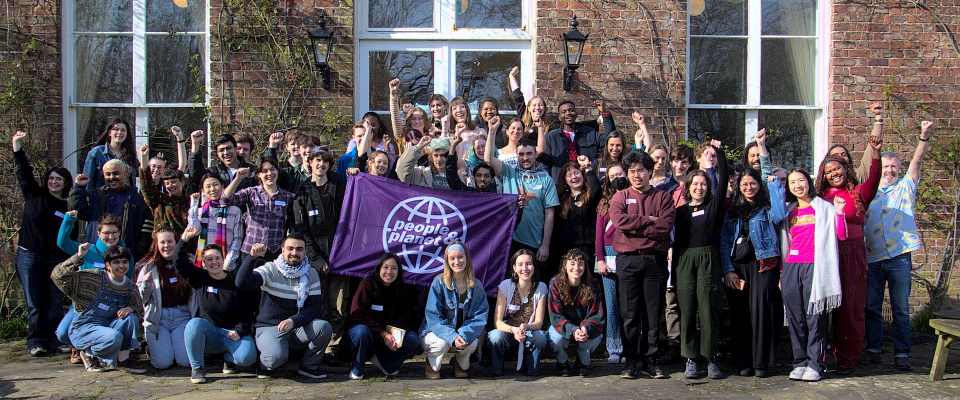 Large group of students with fists raised and People & Planet banner
